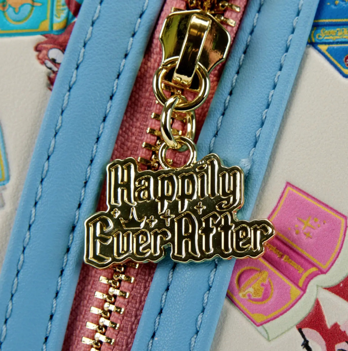 Gold 'Happily Ever After' charm on a blue zipper with a colorful background