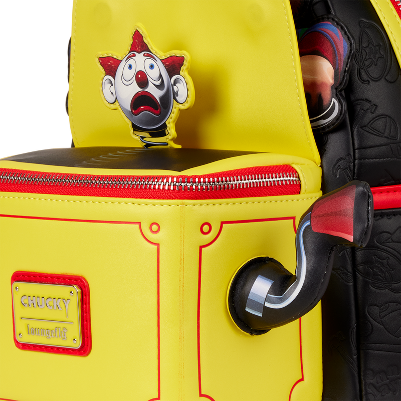 Yellow backpack with a clown face design and 'Chucky' label, held by a person wearing black shoes.