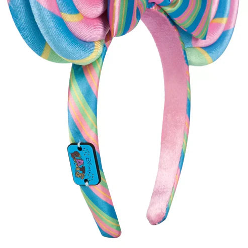 Colorful striped headband with a bow and a plate that states "Disney Eats" on a white background
