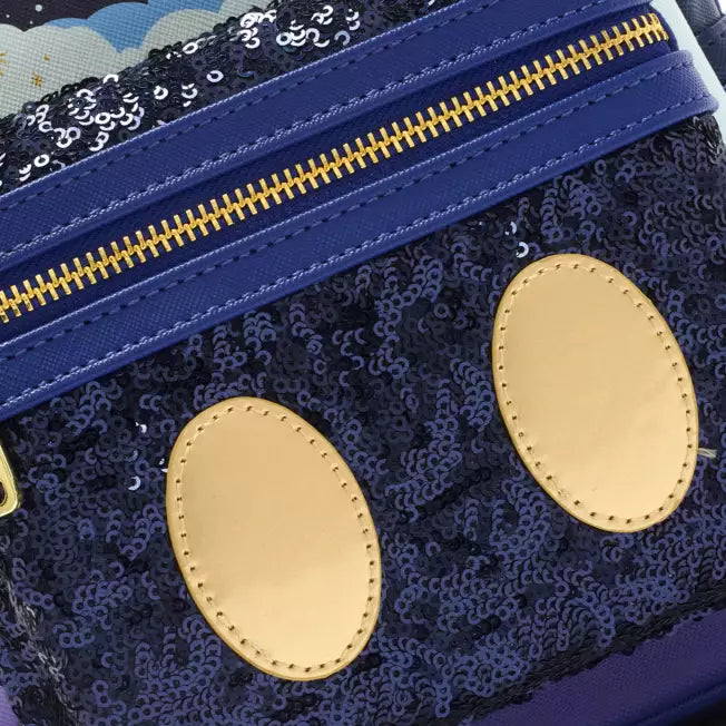 Close-up of a blue front compartment with gold zipper and accents on a dark blue sequin background.