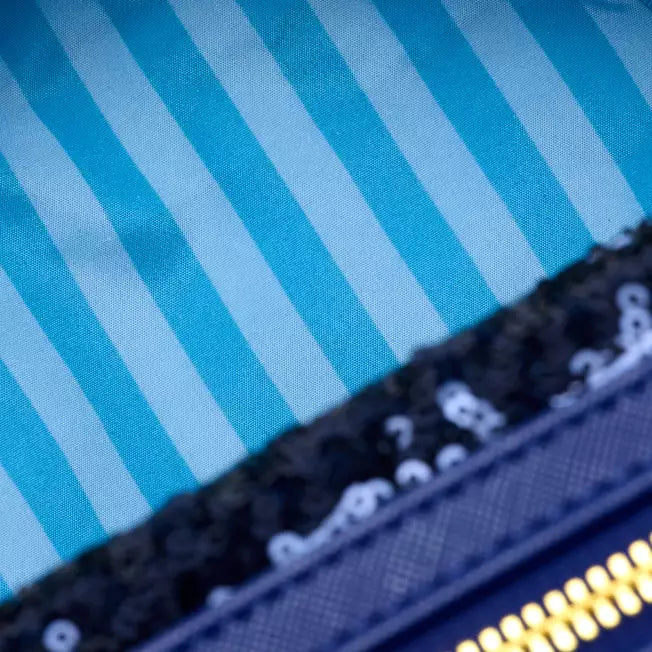 Close-up of a blue and white striped fabric with a black and gold product on top.