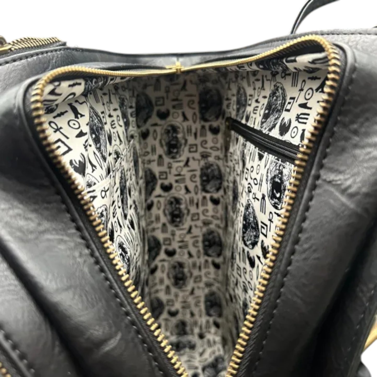 Close-up of a black leather bag with a gold zipper, showing the interior pattern.