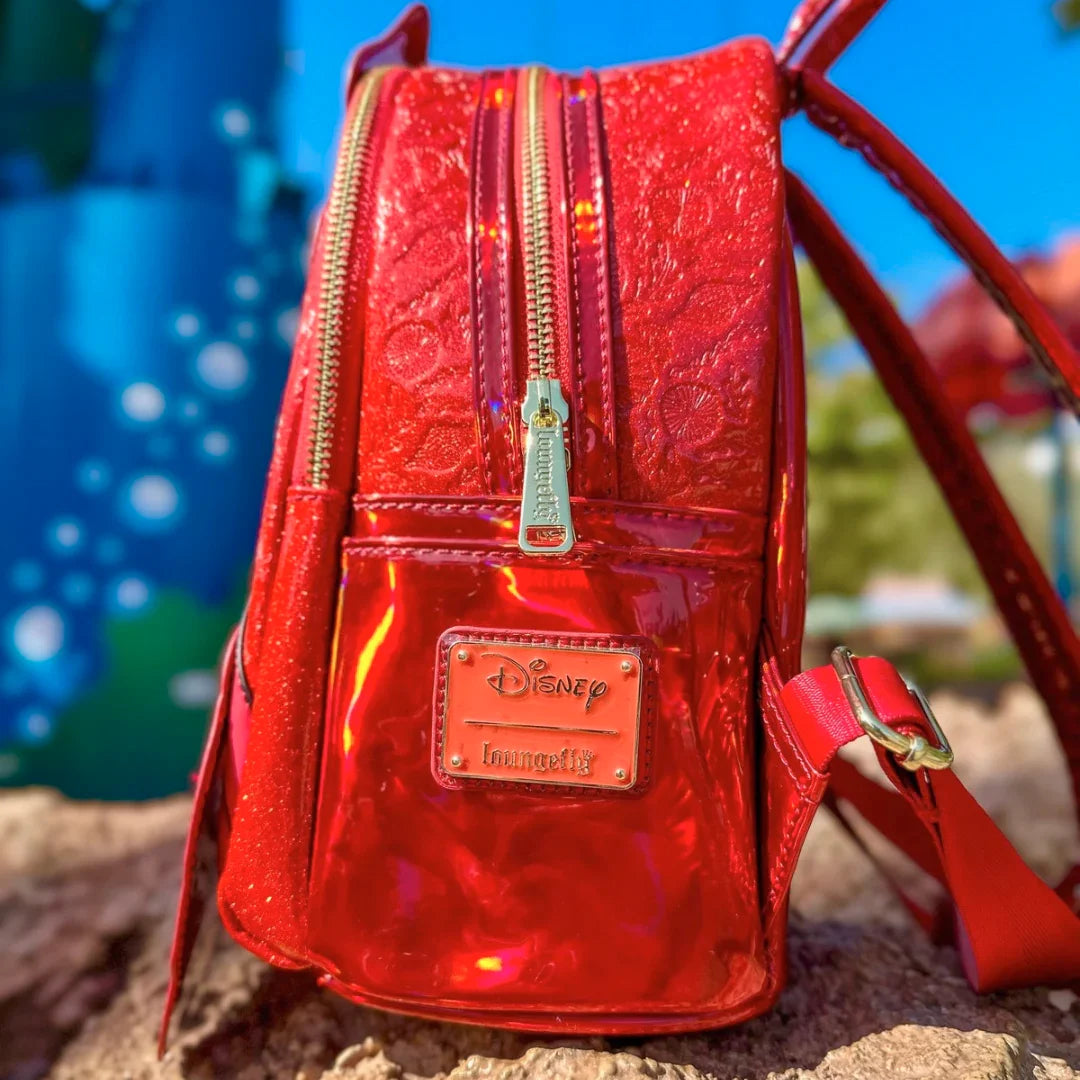Red metallic backpack with Disney Loungefly logo on a blurred outdoor background