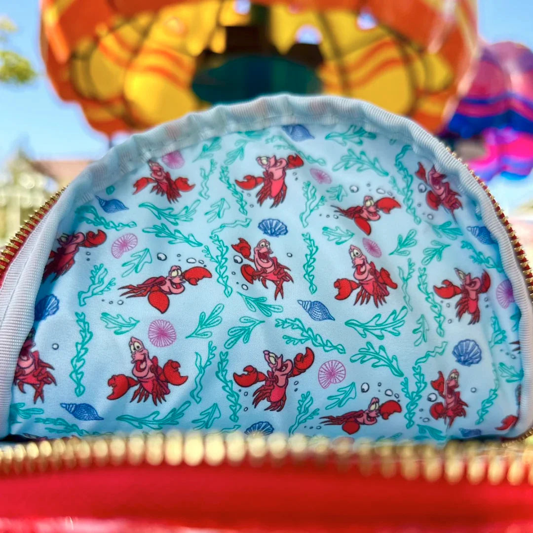 Interior of backpack with Sebastian and ocean-themed designs on a colorful background