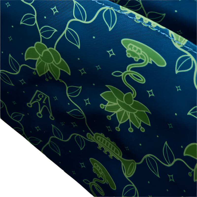 Close-up of inside view of Princess and the Frog Crossbody bag with green floral pattern on blue fabric on a white background.