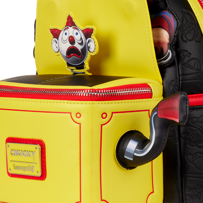 Yellow backpack with a clown face design and 'Chucky' label, held by a person wearing black shoes.