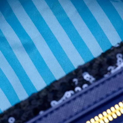 Close-up of a blue and white striped fabric with a black and gold product on top.