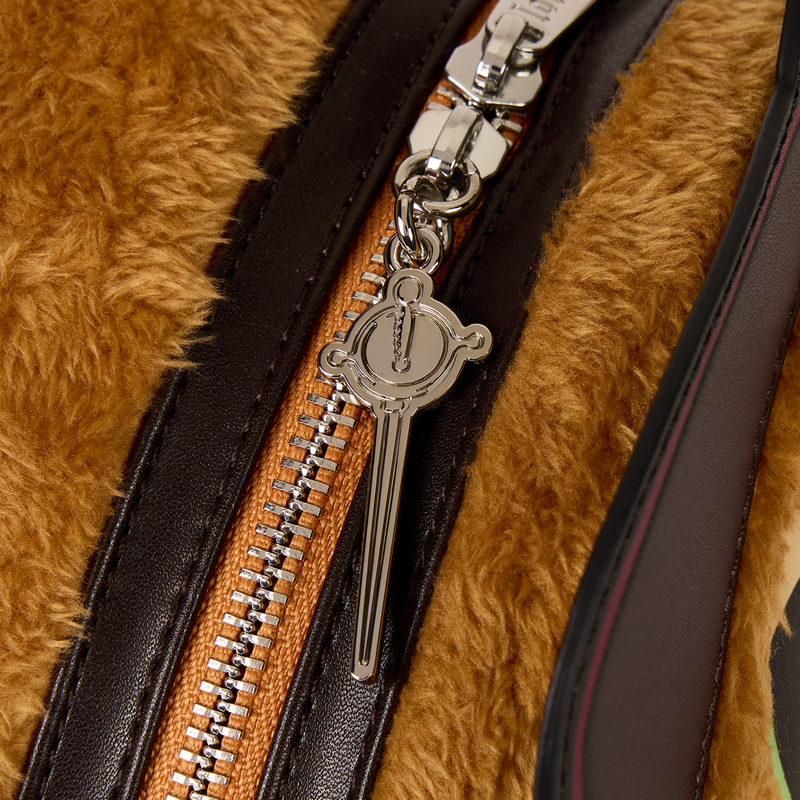 Close-up of a zipper on a fur-textured surface with a decorative pull in the shape of a sword.
