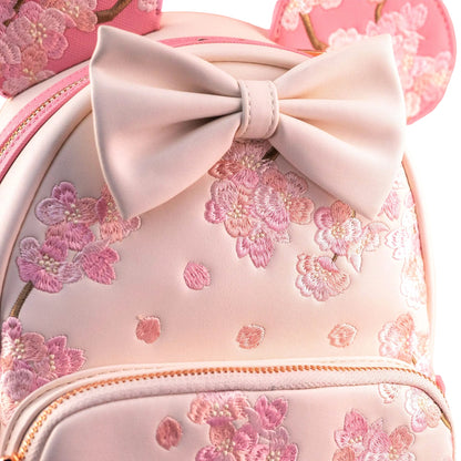 Pink backpack with floral embroidery and a large bow on a white background